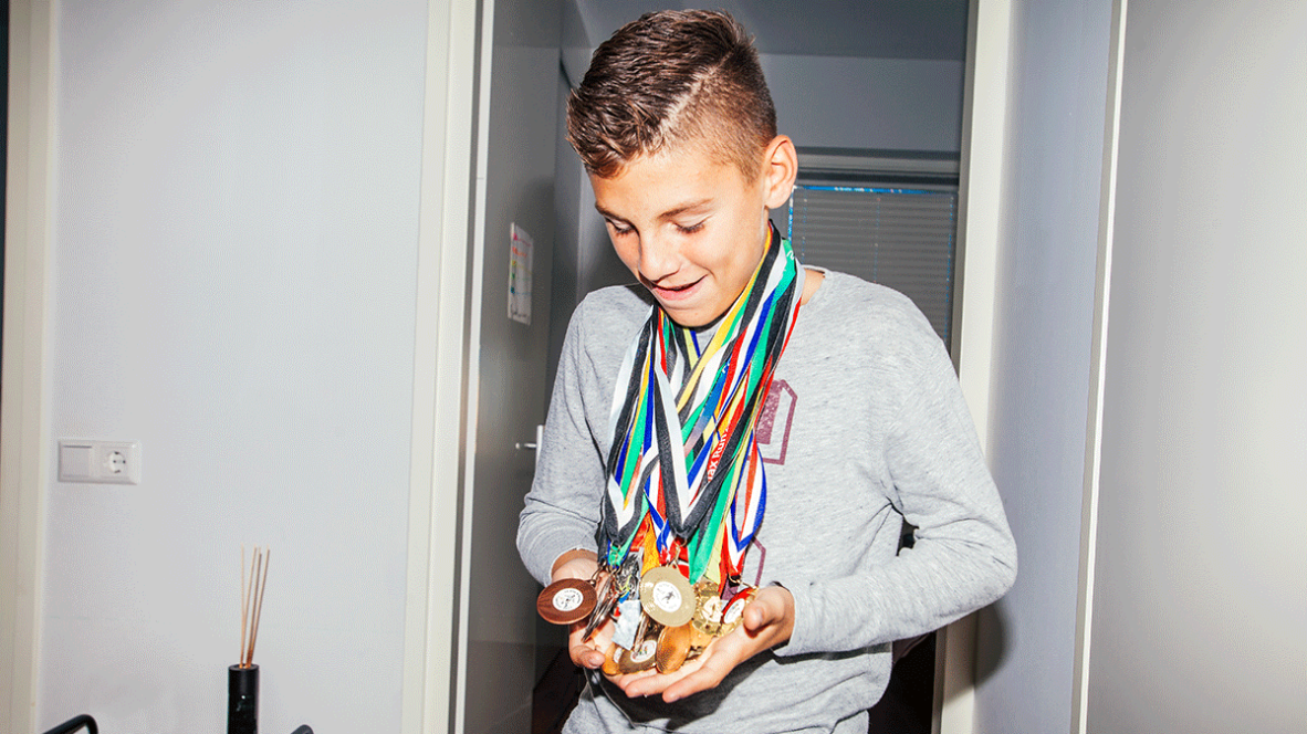 Young boy proudly showing medals